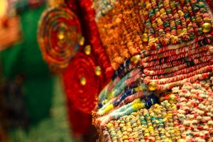 纖維藝術作品的細部，可見多種編織紋理與金屬釘扣的裝飾